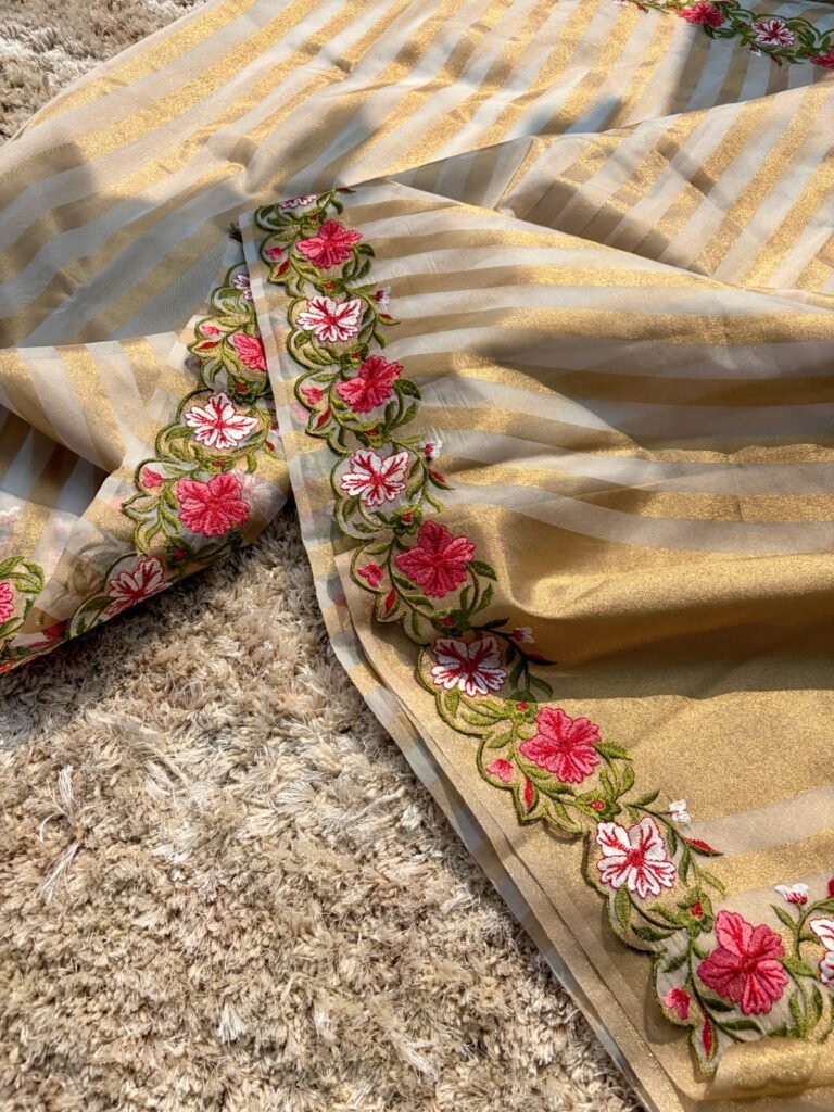 Woman wearing beige Banarasi tissue silk saree with elegant floral embroidery work for festive and wedding occasions